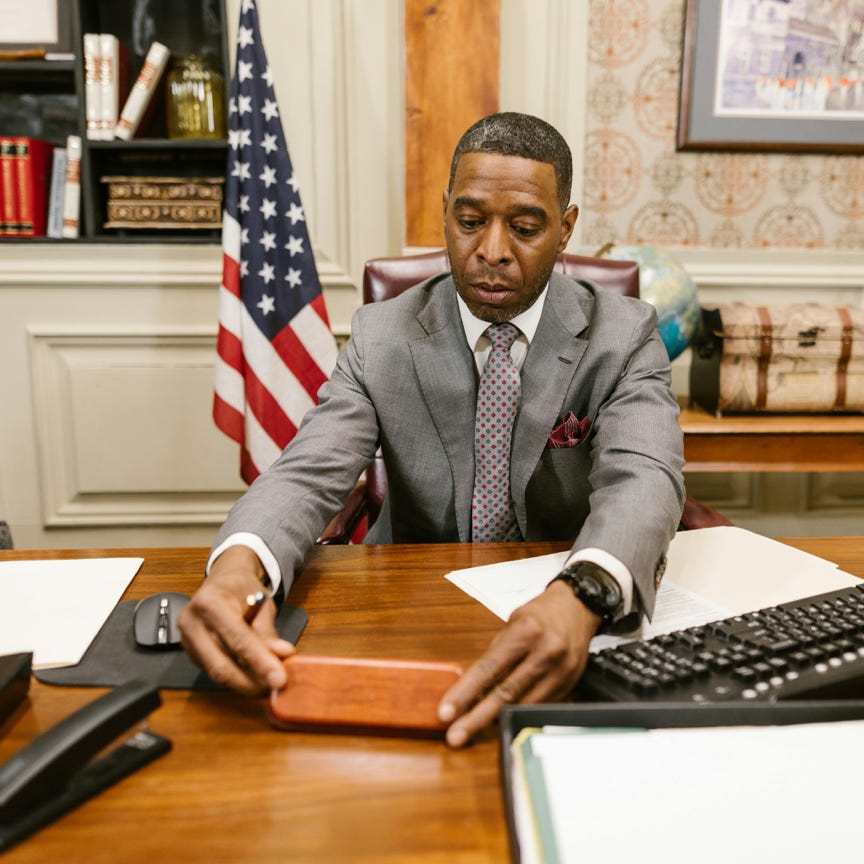 Man in Gray Suit Jacket Sitting on Chair in Front of Laptop Computer